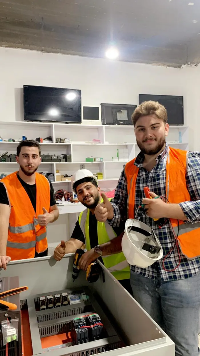 Duhok Automation engineers in safety vests beside an open control panel on site